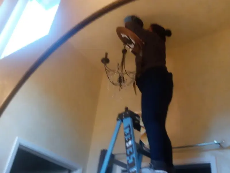 Electrician installing a chandelier in a Burkburnett residence